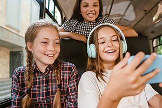 teens watch videos on a phone while riding on a bus